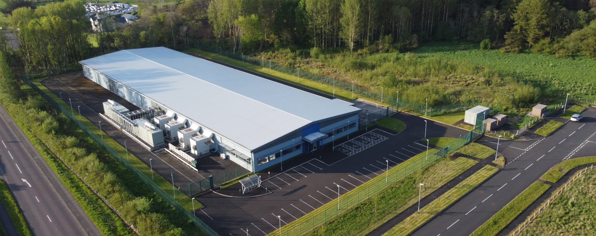 Aerial view of a modern manufacturing facility bordered by woodland